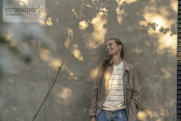 Happy woman standing in front of wall