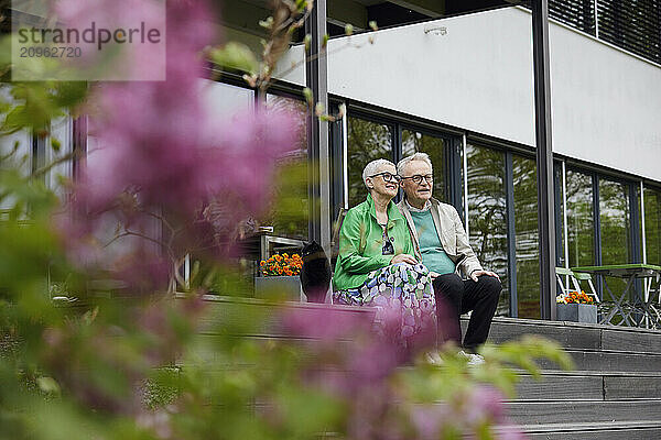 Senior couple sitting on steps in front of their home