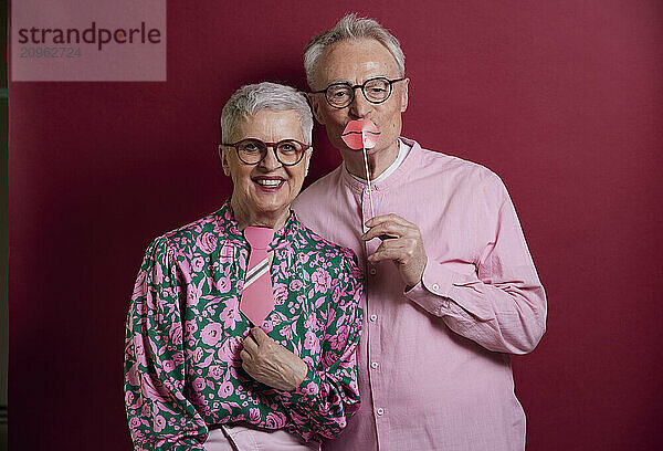 Happy senior couple posing with fake lips and tie