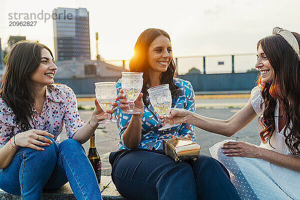 Happy friends toasting wineglasses together at sunset