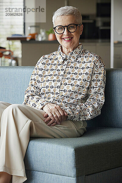 Portrait of smiling senior woman sitting on couch at home