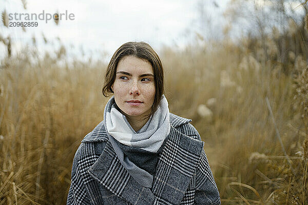 Beautiful woman with warm clothing standing in field