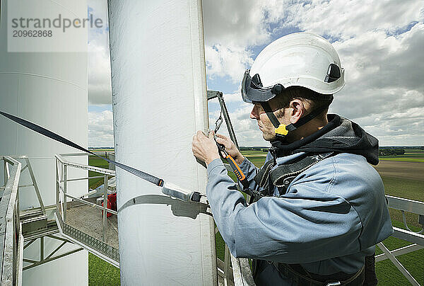 Engineer wearing safety helmet repairing blade of wind turbine