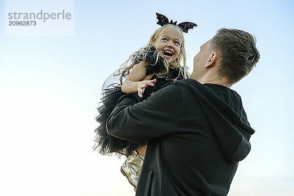 Father carrying daughter and having fun under blue sky