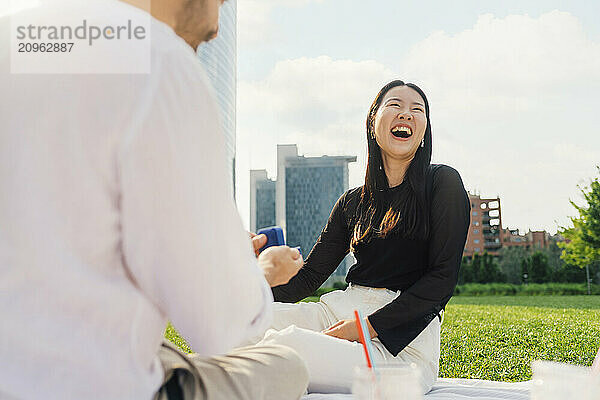 Man surprising happy woman with gift on sunny day in park