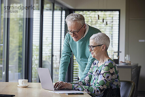 Senior couple using laptop at table at home