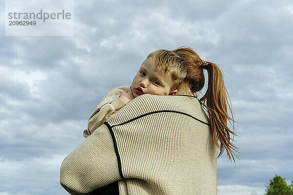 Blond hair boy with mother under cloudy sky