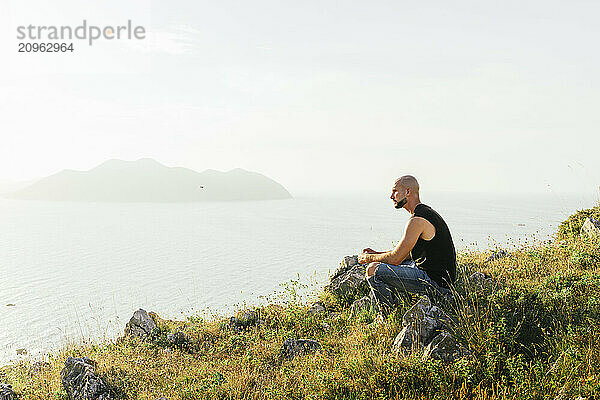 Young man sitting on mountain and looking at view