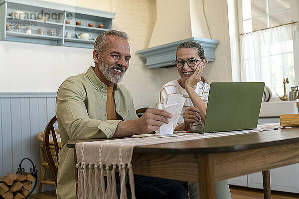 Happy couple examining financial bills at home