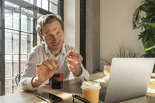 Smiling businessman looking at pencil in office