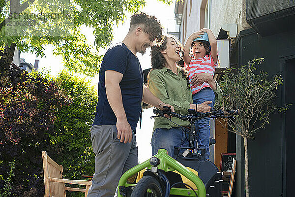 Mother and father enjoying with daughter near cargo bike at street