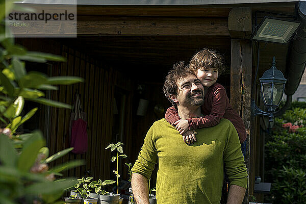 Cute boy embracing father in back yard