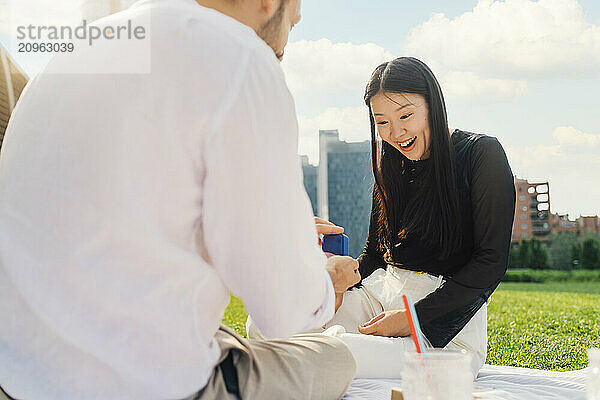 Man surprising woman with gift on sunny day