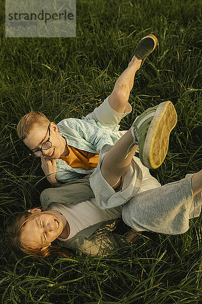 Boy wearing glasses playing with sister in meadow