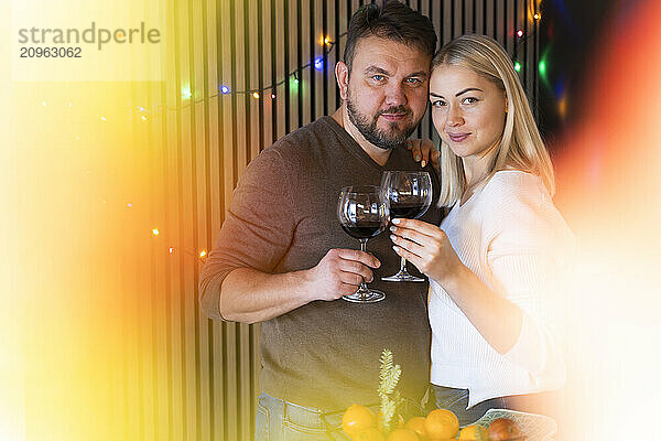 Couple holding red wine glass at home