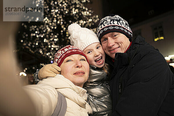 Family taking selfie in front of christmas tree