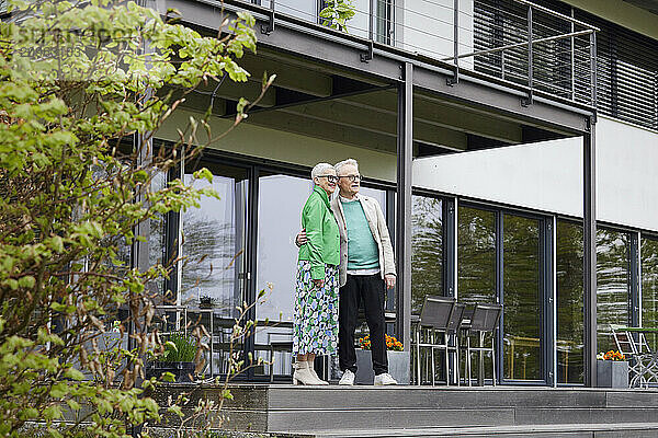 Senior couple standing in front of their home