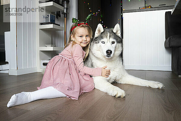 Smiling girl sitting with dog at home