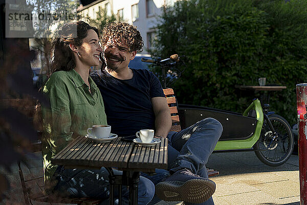 Happy couple sitting on bench at street