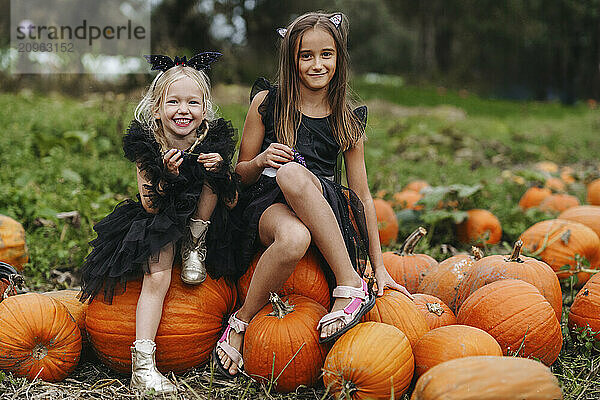 Smiling children sitting over pumpkins in field