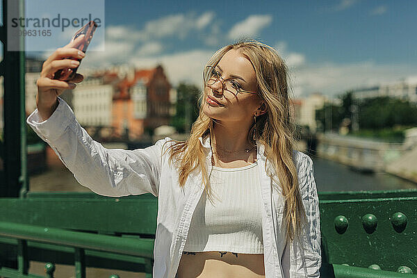 Hipster woman taking selfie on bridge