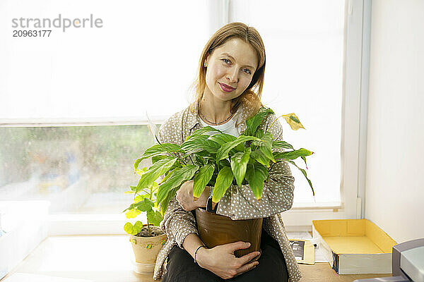 Woman holding potted plant at home