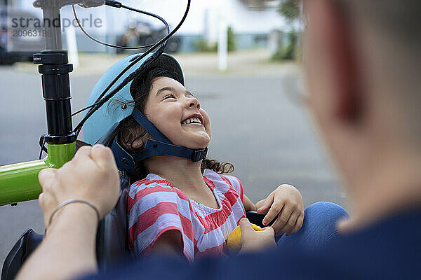 Happy girl wearing helmet sitting in cargo bike