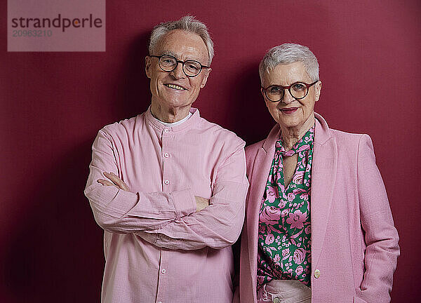 Portrait of confident senior couple against purple background