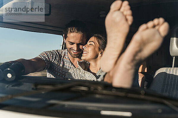 Cheerful young couple sitting in Camper van