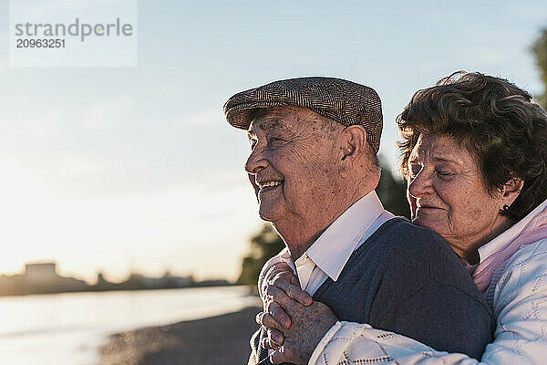 Senior woman embracing man at sunset