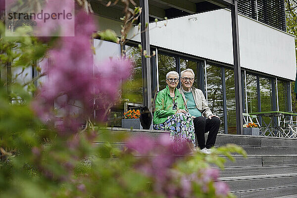 Happy senior couple sitting on steps in front of their home