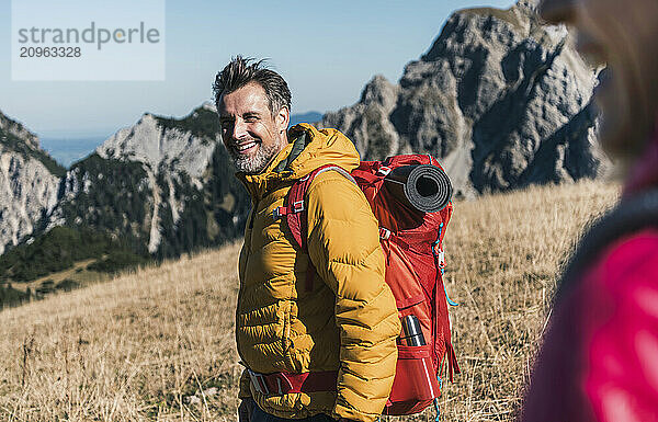 Happy man with backpack standing on mountain