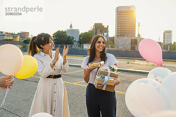 Happy woman applauding and celebrating friends birthday on road at sunset