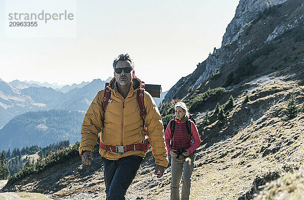 Man wearing backpack hiking with friend on mountain