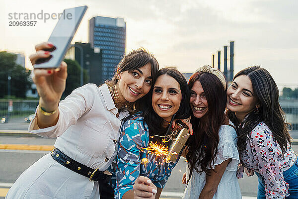 Happy woman taking selfie with friends at sunset