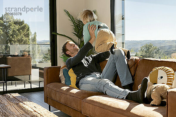 Father and son having fun together on sofa at home