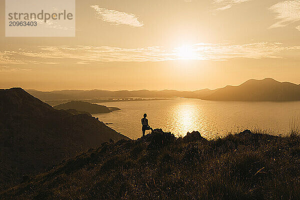 Young woman standing near river at sunrise