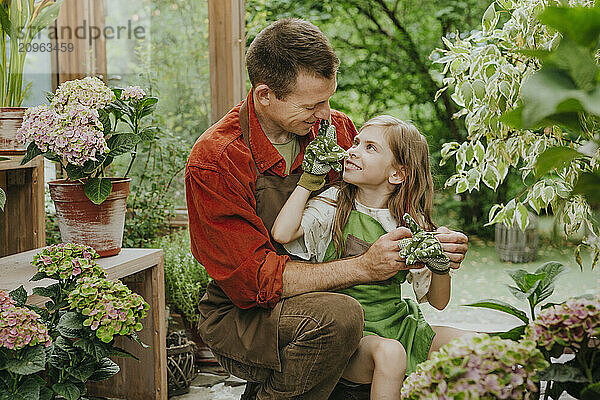 Playful girl spending leisure time with father in plant nursery