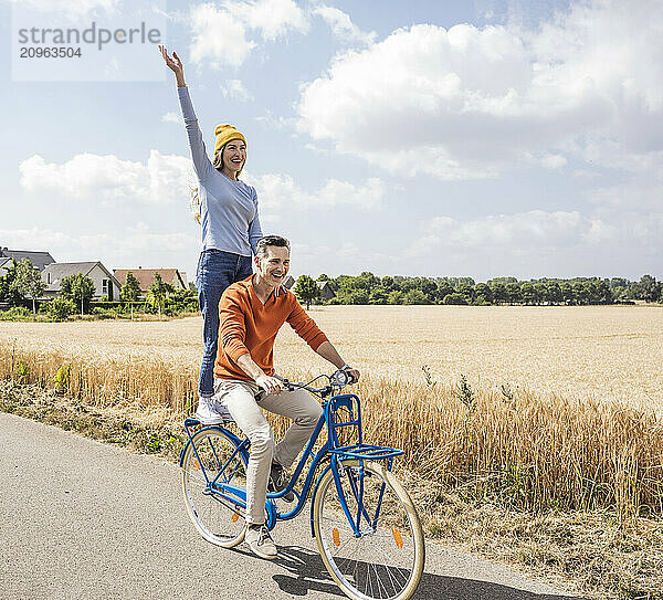 Happy mature man giving bicycle ride to woman at field