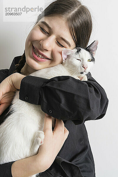 Teenage girl with braces hugging a white cat