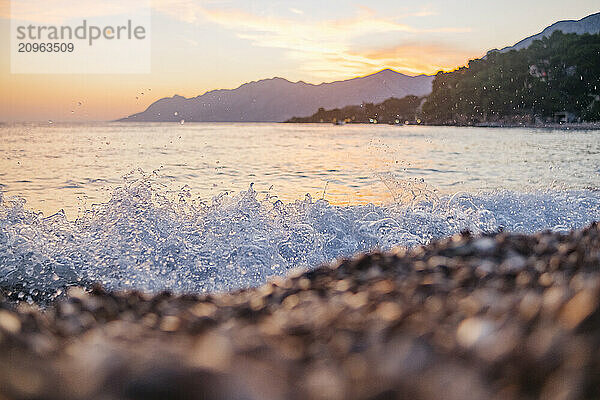 Waves crashing near rocks of Brela beach at sunset