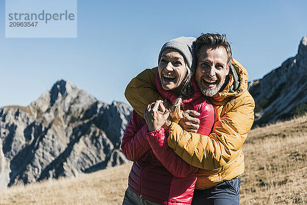 Happy man embracing friend standing on mountain