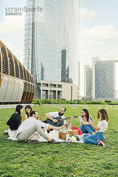 Man playing guitar with friends together having fun in front of buildings