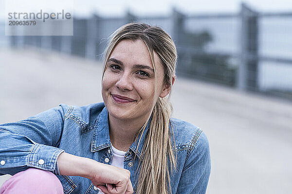 Blond woman sitting with hand on knee at bridge