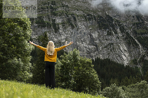 Girl with arms outstretched standing near mountains