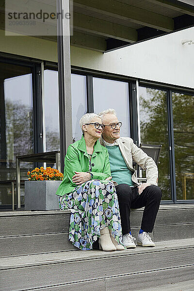 Senior couple sitting on steps in front of their home