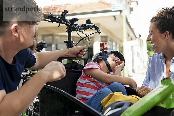 Father and mother enjoying with daughter sitting in cargo bike