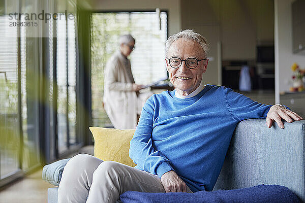 Portrait of smiling senior man sitting on couch at home