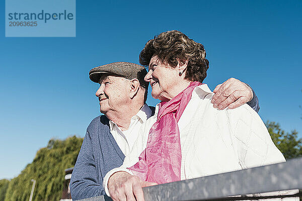 Happy senior couple standing together under blue sky on sunny day