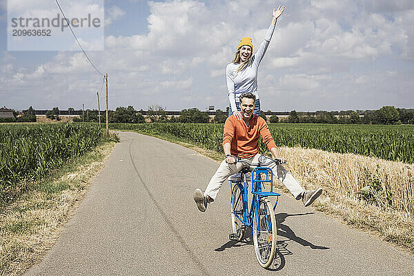 Cheerful mature man giving bicycle ride to woman on road